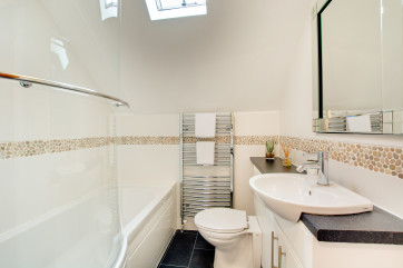 Modern and bright the bathroom benefits from bath with over-bath shower, vanity washbasin and wc