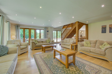 Another view of sitting room showing open-plan staircase and patio doors to garden.