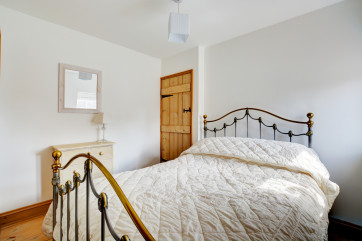 Pretty double bedroom with wrought iron double bed, feature fireplace and pine floorboards