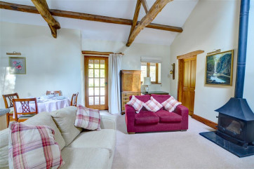 The open plan living room is comfortably furnished, with sitting room area and a circular dining table and chairs