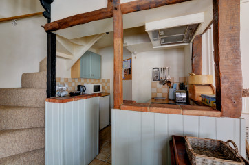 Compact kitchen with appliances situated at the bottom of the cottage style stairs.