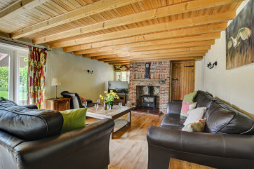 Looking across the comfortable sitting room towards the charming fireplace and woodburner.