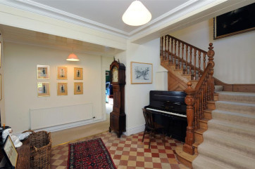 Enter into the welcoming hall with impressive pine staircase.