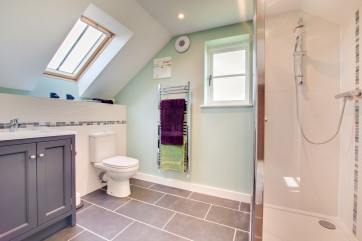 The modern and bright shower room benefits from wash basin, wc and walk in shower