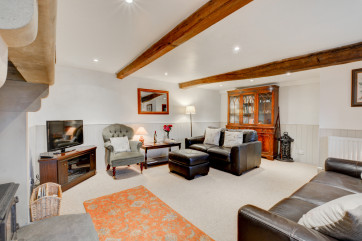 Spacious lounge with beamed ceiling and solid fuel stove