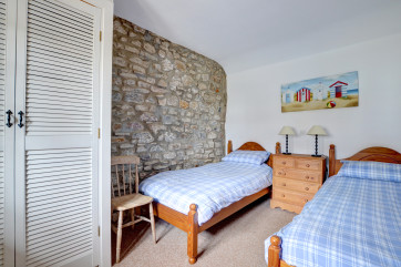 Twin bedroom has original stone wall and fitted wardrobe