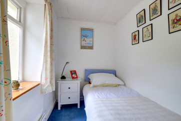 Tidy sized single bedroom with bedside cabinet and a chair