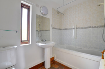 Bath shower room has shower over bath, sink and toilet