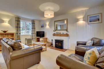 The stylish living /dining room has comfy leather sofas and a welcoming wood burning stove