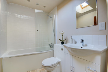 The ensuite off of bedroom one has a curved bath with an over bath shower, washbasin and wc