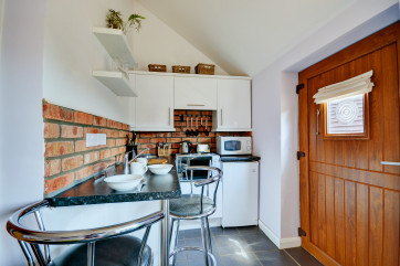 The compact kitchen area has an electric mini fan-assisted oven and two rings, full-size fridge with icebox, microwave and breakfast bar with two bar stools