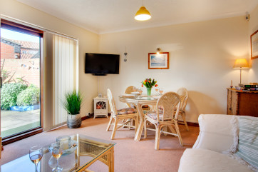 Sitting room with comfortable seating, TV and dining area with access to the secluded patio