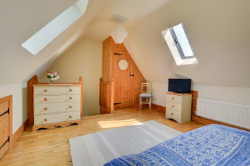 Velux windows and wooden flooring covered with a striped rug.