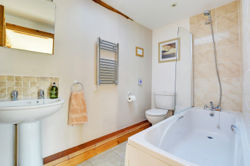 The modern bathroom has a bath and over bath shower, with lovely attention to detail