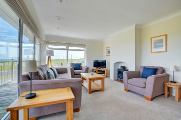 First floor pleasantly furnished with comfortable seating, electric woodburner-style fire and door to the balcony with splendid sea views