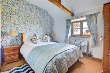 An elegant bedroom with a double bed and exposed beams