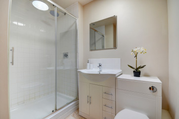 The fully tiled shower room has a large shower enclosure with a sliding glass door 