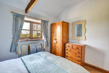 Characterful double bedroom with a wardrobe and chest of drawers for storage