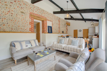 Open plan living room with comfortable seating, exposed brickwork & beams.