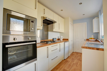 Kitchen with built-in electric oven, gas hob, fridge with icebox, combination microwave and washing machine