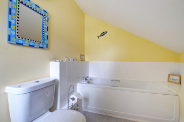 A bathroom with white suite and brightly coloured walls.