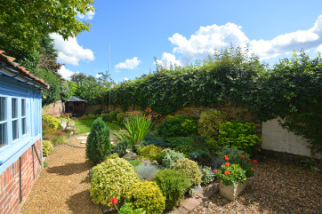 Very pretty walled garden with rockery and gravelled pathway leading to further garden and lawn area.