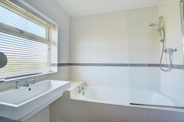 Bathroom with white bath and overbath shower.