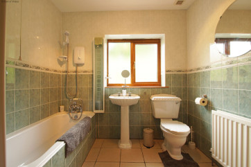Family bathroom with bath and shower above, radiator, WC & washbasin.
