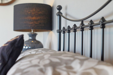 Stylish large downstairs double bedroom has a black iron bed