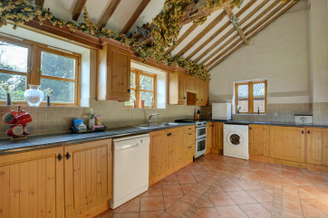 The kitchen is at the rear of the house, with a fitted electric cooker and washing machine. The exposed beams add character to the room