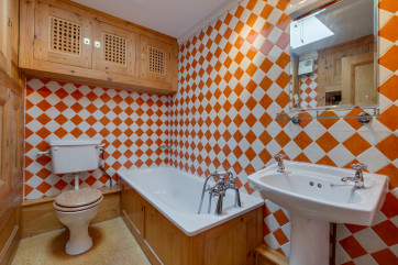 Colourfully tiled bathroom with a bath, wc & washbasin 