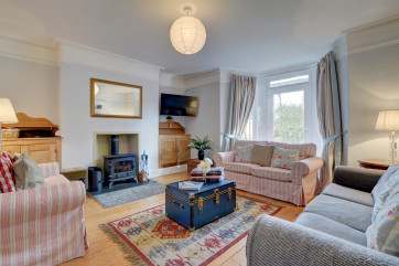 The cosy living area has 3 sofas, a wood burner for the cooler seasons, large wall mounted TV and glazed door to garden area