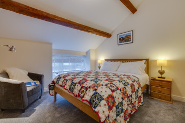 King sized bed in beamed bedroom