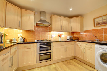 Maple units and granite style work surfaces complement the kitchen and dining areas to the rear