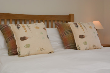 Bed made up with white linen and tasteful cushions