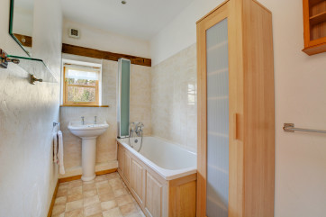 The bathroom is on the first floor and has a white suite and pale wood cupboards