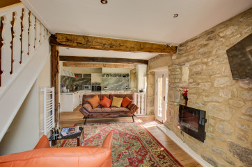 Open plan living area, with exposed stone walls, comfortable seating and well equipped kitchen