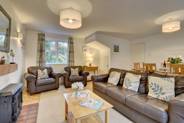 The stylish living /dining room has comfy leather sofas and a welcoming wood burning stove
