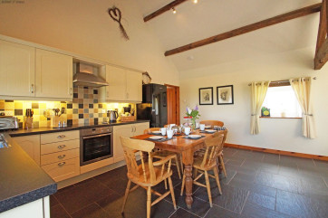 A spacious, cream 'shaker' style kitchen with a farmhouse pine table.