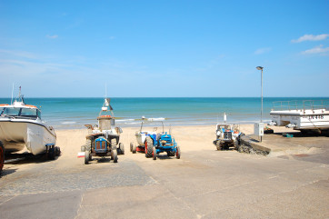 Boats and tractors lined up on the beach.