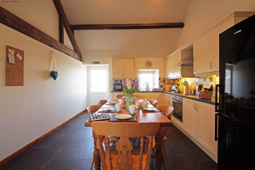 A spacious, cream 'shaker' style kitchen with a farmhouse pine table.