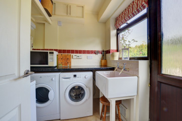 Utility room with washing machine, tumble dryer and sink