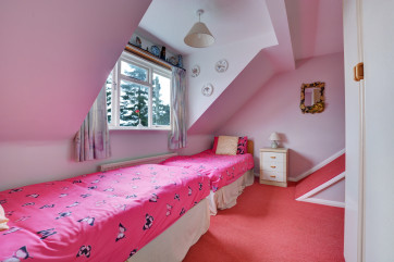 Twin bedroom with sloping ceilings and large window, ideal for children