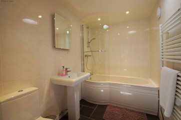 Stylish bathroom with a P shaped bath, shower over & heated towel rail