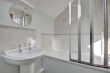 Bathroom with shower over bath, wash basin and toilet.