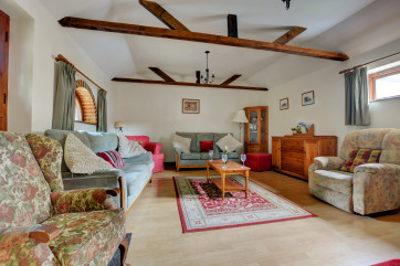Spacious and light sitting room with a feature fireplace, exposed brickwork and lovely beams