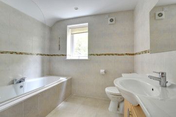 Family bathroom with toilet, whb & shower over bath.