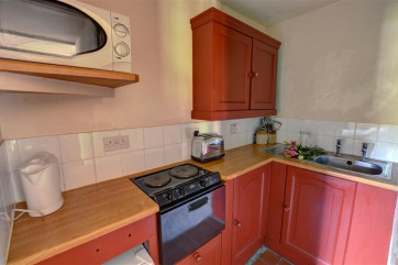 The tiny kitchen has fitted cupboards and small appliances