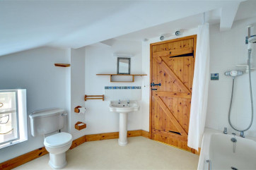 The main bathroom is spacious, with white suite and shower over the bath