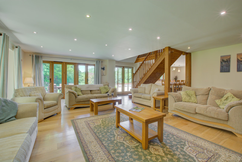 Another view of sitting room showing open-plan staircase and patio doors to garden.